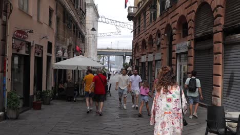 Grupos-De-Personas-Caminando-Por-Estrechas-Calles-Pavimentadas-Con-Edificios-Tradicionales-Y-Tiendas-A-Los-Lados.