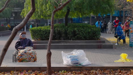 Un-Anciano,-Con-Una-Máscara,-Descansa-En-Su-Silla-De-Ruedas-En-El-Parque-Durante-El-Cierre-De-Covid-En-Beijing,-China