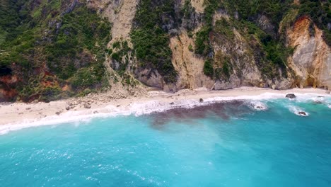 Drone-panning-in-front-of-the-rocky-limestones-behind-the-secluded-Petanoi-beachfront,-located-in-the-island-of-Kefalonia-in-the-Western-Coast-of-Greece