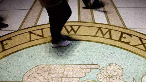 People-walking-near-state-seal-on-the-floor-inside-New-Mexico-capitol-building-in-Santa-Fe,-New-Mexico-with-video-panning-right-to-left