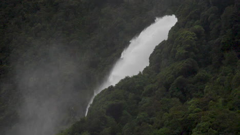 Slow-Motion-shot-of-a-large-waterfall-in-Milford-Sound-after-a-rain-storm-with-mist---Piopiotahi,-New-Zealand