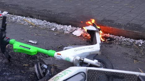 Electric-scooter-on-fire-falling-on-the-ground-in-the-city-street-of-Brussels,-Belgium---Slow-motion