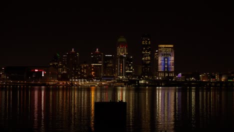 Louisville,-Kentucky-skyline-with-Ohio-River-at-night-and-boat-moving-with-wide-shot-stable