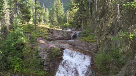 Virginia-Creek-Waterfall-running-into-Virginia-Creek-in-Glacier-National-Park,-tilt-down