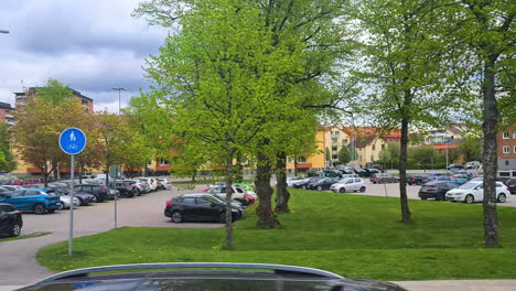 Katrineholm,-Sweden,-Residential-Buildings-and-Cars-on-Parking-Lot-on-Cloudy-Summer-Day,-View-From-Moving-Vehicle