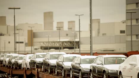 New-cars-on-freight-train-in-industrial-area,-overcast-day