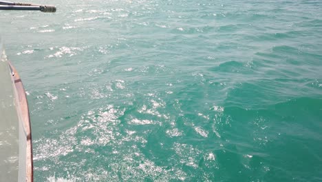 Waves-crash-against-the-side-of-a-boat-on-the-azure-sea,-Zakynthos-island,-Greece