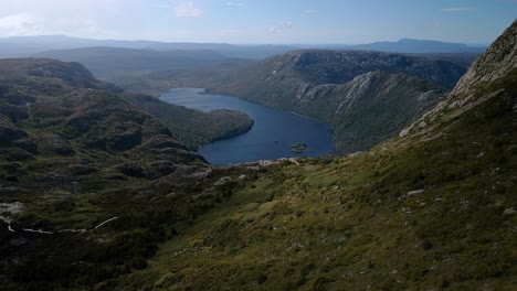 Drone-shot-of-a-calm-lake-with-green-hills-and-skyscape-at-background