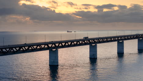 Vivid-golden-hour-aerial-dolly-view-of-traffic-flow-over-iconic-Oresund-bridge