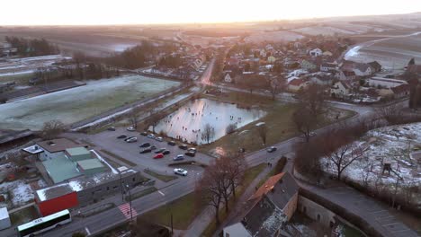 Panoramablick-Auf-Die-Verschneite-Landschaft-Und-Die-Leute,-Die-Auf-Dem-Zugefrorenen-See-Schlittschuh-Laufen---Drohnenaufnahme