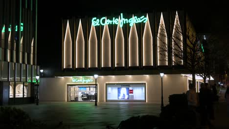Shoppers-walk-past-the-Spanish-biggest-department-store-company,-El-Corte-Ingles,-building-during-nighttime-in-Spain