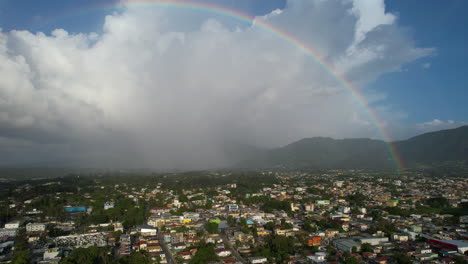 Toma-Aérea-De-Establecimiento-De-La-Ciudad-De-Jarabacoa-Con-Un-Hermoso-Arco-Iris-En-El-Cielo.