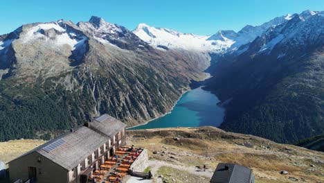 Cabaña-Olpererhutte-Y-Lago-De-Montaña-Schlegeis-En-Los-Alpes-De-Zillertal,-Austria---Pedestal-Aéreo-4k