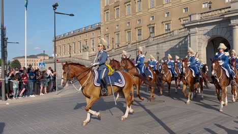 Guards-ride-horses-by-Swedish-Royal-Palace-on-national-day,-slo-mo