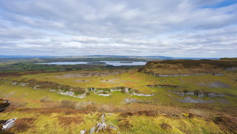 Panorama-motion-timelapse-of-rural-nature-farmland-with-rocks-in-the-foreground-valley-and-hills-and-lake-in-distance-during-sunny-cloudy-day-viewed-from-Carrowkeel-in-county-Sligo-in-Ireland