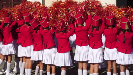 Chicas-Majorette-Con-Uniformes-Rojos-Y-Blancos-Agitando-Pompones-En-La-Práctica-Grupal