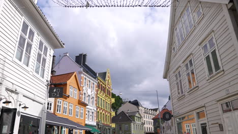 Bergen,-Norway,-Walking-on-Street-Between-Authentic-Buildings-on-Sunny-Day,-Low-Angle-Slow-Motion