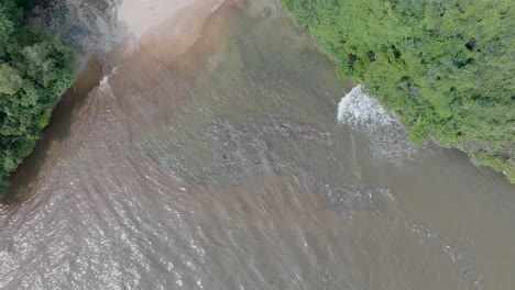 Von-Oben-Nach-Unten-Schnell-Absteigende-Drohnenaufnahme-über-Verschmutztem,-Schlammigem-Abwasser-Und-Schwimmendem-Müll-Mit-Trümmern-über-Einem-Toten-Korallenriff,-Das-Sich-Mit-Türkisfarbenem-Wasser-Und-Einer-Tropischen-Küste-In-Bali,-Indonesien-Vermischt