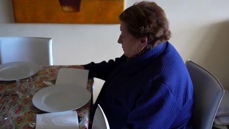 Abuela-Acomodándose-En-La-Mesa,-Esperando-Pacientemente-La-Reunión-Familiar-A-La-Hora-De-Comer