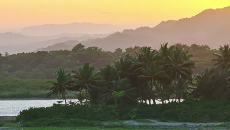 Vívido-Cielo-Del-Atardecer-Detrás-De-Montañas-Con-Palmeras-En-La-Costa-Caribeña