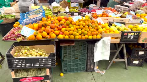 Trabajador-Del-Mercado-Organizando-Productos-Y-Clientes-Recogiendo-Frutas-En-Lisboa,-Portugal.