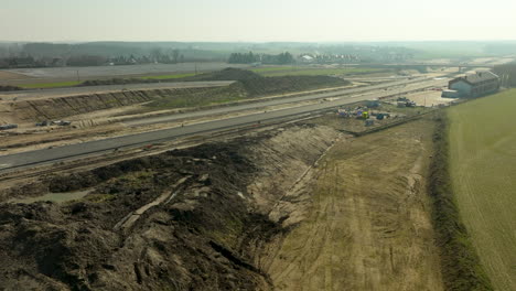 Luftaufnahme-Einer-Ausgedehnten-Autobahnbaustelle-Mit-Erdhügeln-Und-Ausrüstung