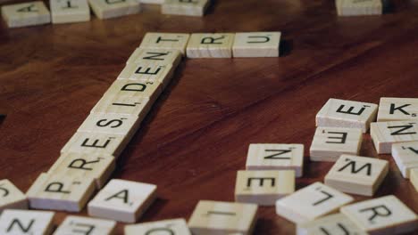 Finger-Bewegen-Scrabble-Buchstabensteine,-Um-Die-Wörter-„Präsident“-Und-„Trump“-Zu-Bilden