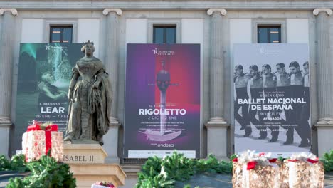 View-of-the-Isabel-II-statue-seen-in-the-foreground-in-front-of-the-Teatro-Real-,-Spain's-foremost-institution-for-the-performing-and-musical-arts,-at-Isabel-II-plaza-in-Spain