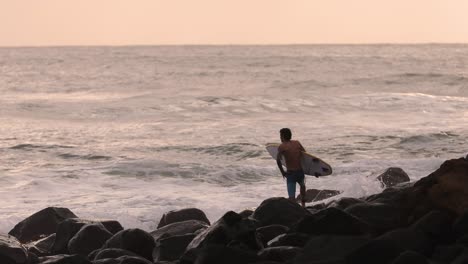 View-of-surfer-rock-hopping-at-Burleigh-Heads-at-sunrise,-Gold-Coast,-Australia