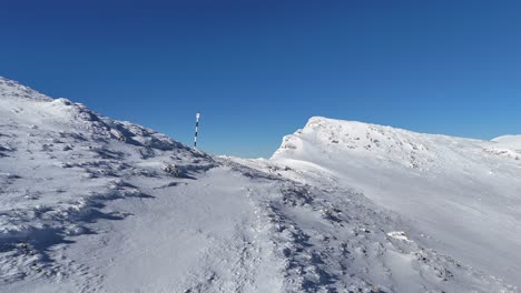 Snow-covered-slopes-of-Bucegi-with-Iezer-Papusa-and-Piatra-Craiului-in-the-distance,-blue-sky