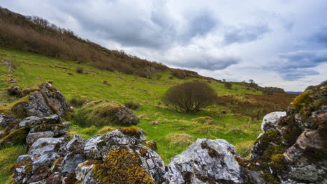 Timelapse-of-rural-nature-farmland-with-line-of-rocks-in-the-foreground-located-in-grass-tree-field-during-cloudy-day-viewed-from-Carrowkeel-in-county-Sligo-in-Ireland