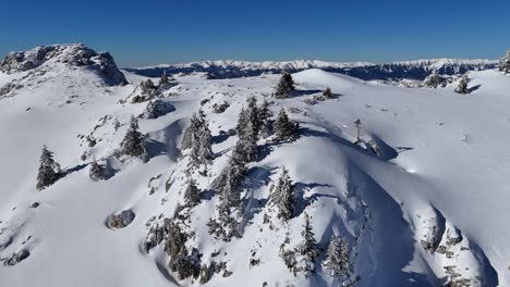 Snow-covered-Bucegi-Mountains-under-clear-blue-sky,-rugged-terrain