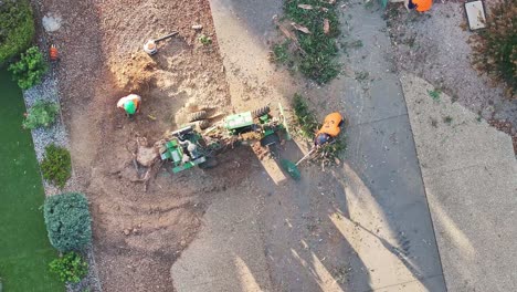 Yarrawonga,-Victoria,-Australia---6-March-2024:-Overhead-of-workers-raking-rubbish-and-stump-grinder-throwing-out-chips-and-dust-in-a-suburban-street