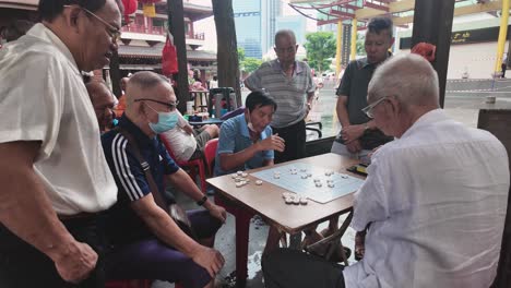 A-group-of-elderly-chinese-men-playing-board-games-on-Sundays-in-Chinatown-square-of-Singapore