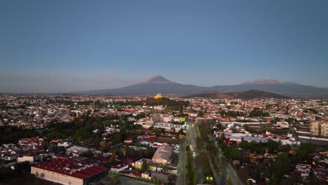 Drone-rising-over-the-cityscape,-toward-the-Our-Lady-of-Remedies-church-in-San-Andrés-Cholula,-Mexico