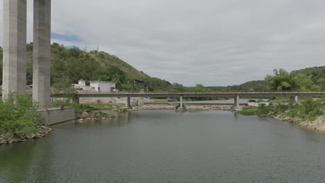 Drone-flying-under-bridge-crossing-Rio-Chavon-river,-Dominican-Republic