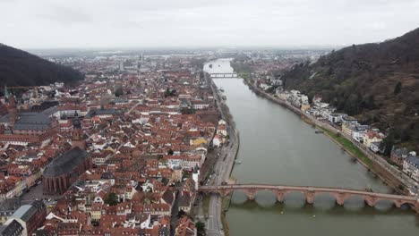 Heidelberg-Germany-old-bridge-and-iconic-dark-church-along-river-canal,-aerial-establishing-dolly