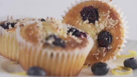 Frisches,-Leckeres,-Zuckerhaltiges-Gebäck,-Blaubeeren-Und-Schokoladenmuffins-In-Einem-Cupcake-Papierhalter,-Der-Auf-Einem-Weißen-Tellerhintergrund-Rotiert