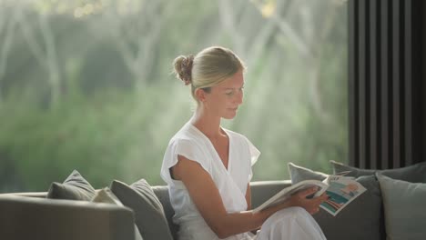 Pretty-blond-woman-reading-magazine-with-morning-light-rays-in-background