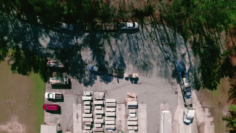 Semi-truck-driver-with-flatbed-load-entering-warehouse-while-hotshot-pickup-truck-is-loaded-by-forklift-with-vinyl-siding