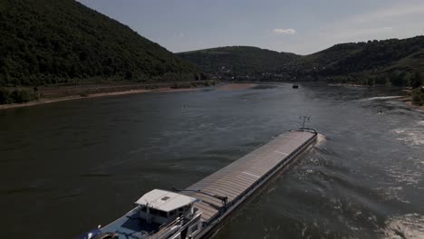 Lastkahn-Flachbodenboot-Wird-Von-Einem-Schlepper-Den-Rhein-Hinunter-In-Oberwesel,-Deutschland-Geschoben