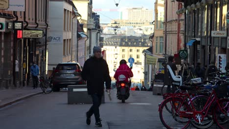 Person-rides-food-delivery-scooter-for-Foodora-on-street-in-Stockholm