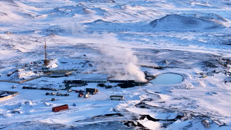 Myvatn-thermal-spa-in-winter,-construction-nearby,-steam-rising,-snowy-landscape,-aerial-view