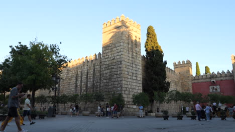 Gente-Fuera-De-Las-Murallas-Medievales-Y-La-Puerta-Del-León,-Entrada-Del-Real-Alcázar-De-Sevilla-En-España