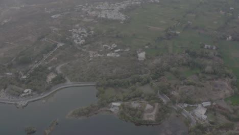 Luftaufnahme-Einer-Drohne,-Die-Vorwärts-Geht-Und-Viele-Große-Berge-Und-Wohnhäuser-Sowie-Große-Felder-Zeigt