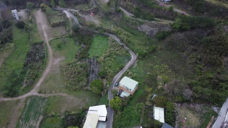 Rural-landscape-with-winding-road-and-houses-during-the-day,-aerial-view