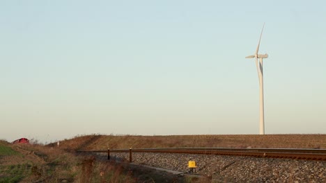 Roter-Güterzug-Der-Deutschen-Bahn-Fährt-In-Der-Abenddämmerung-Mit-Einer-Windkraftanlage-Im-Hintergrund-Vorbei