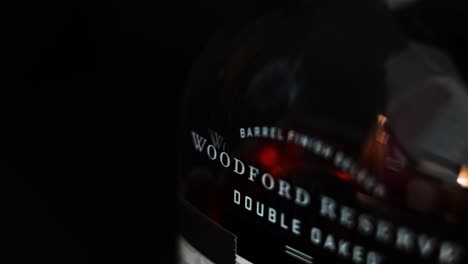 Nahaufnahme-Des-Etiketts-Auf-Einer-Flasche-Woodford-Reserve-Double-Oaked-Kentucky-Straight-Bourbon-Whiskey-Aus-Versailles,-Kentucky-Mit-Einem-Dunkelschwarzen-Hintergrund-Und-Geringer-Tiefenschärfe