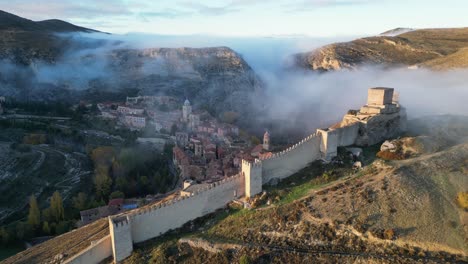Albarracin-Fortress,-Village-and-Foggy-Mountain-Valley-in-Teruel,-Aragon,-Spain---Aerial-4k