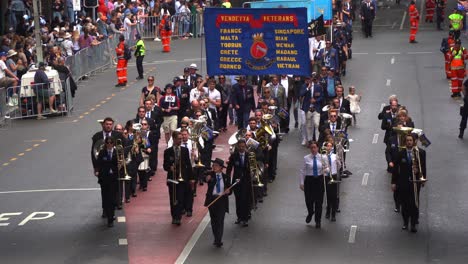 Marching-band-and-Vendetta-veterans-walking-down-Adelaide-street-with-crowds-gathered-alongside,-honouring-the-memory-of-those-who-served,-Brisbane-city